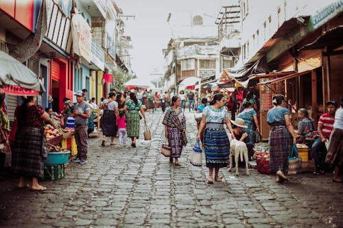 People walking down a cobblestone street in a market