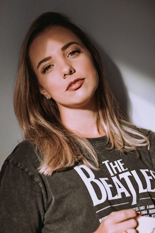 Portrait Photo of Woman in Beatles T-shirt Leaning on Wall