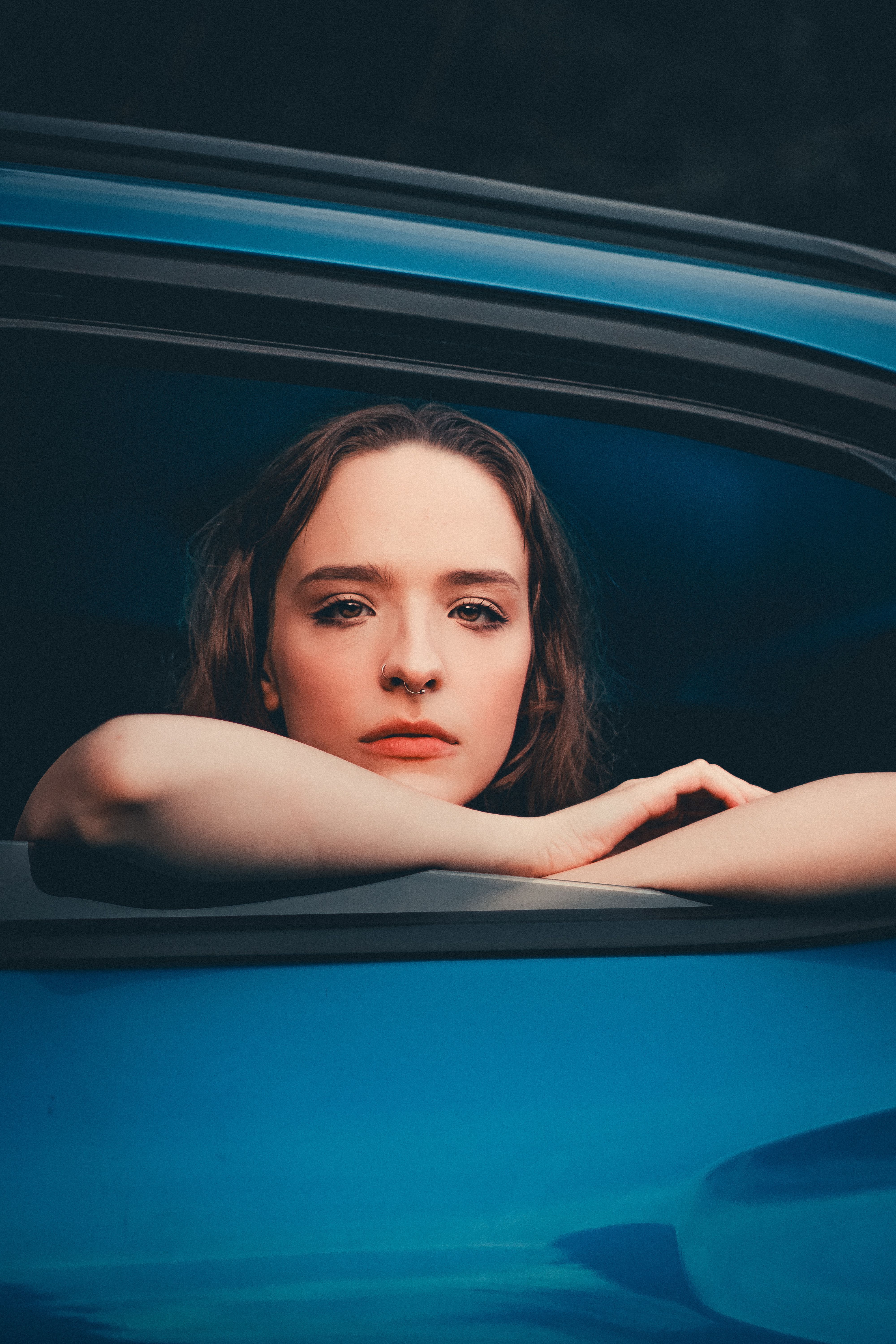Portrait of Brunette Woman Sitting in Blue Car · Free Stock Photo