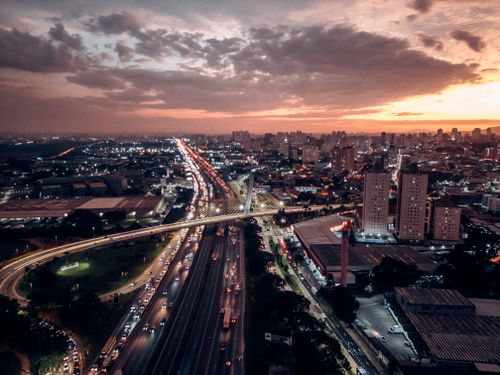 Free Breathtaking aerial view of Macedo, Brazil at sunset with bustling traffic and illuminated skyline. Stock Photo
