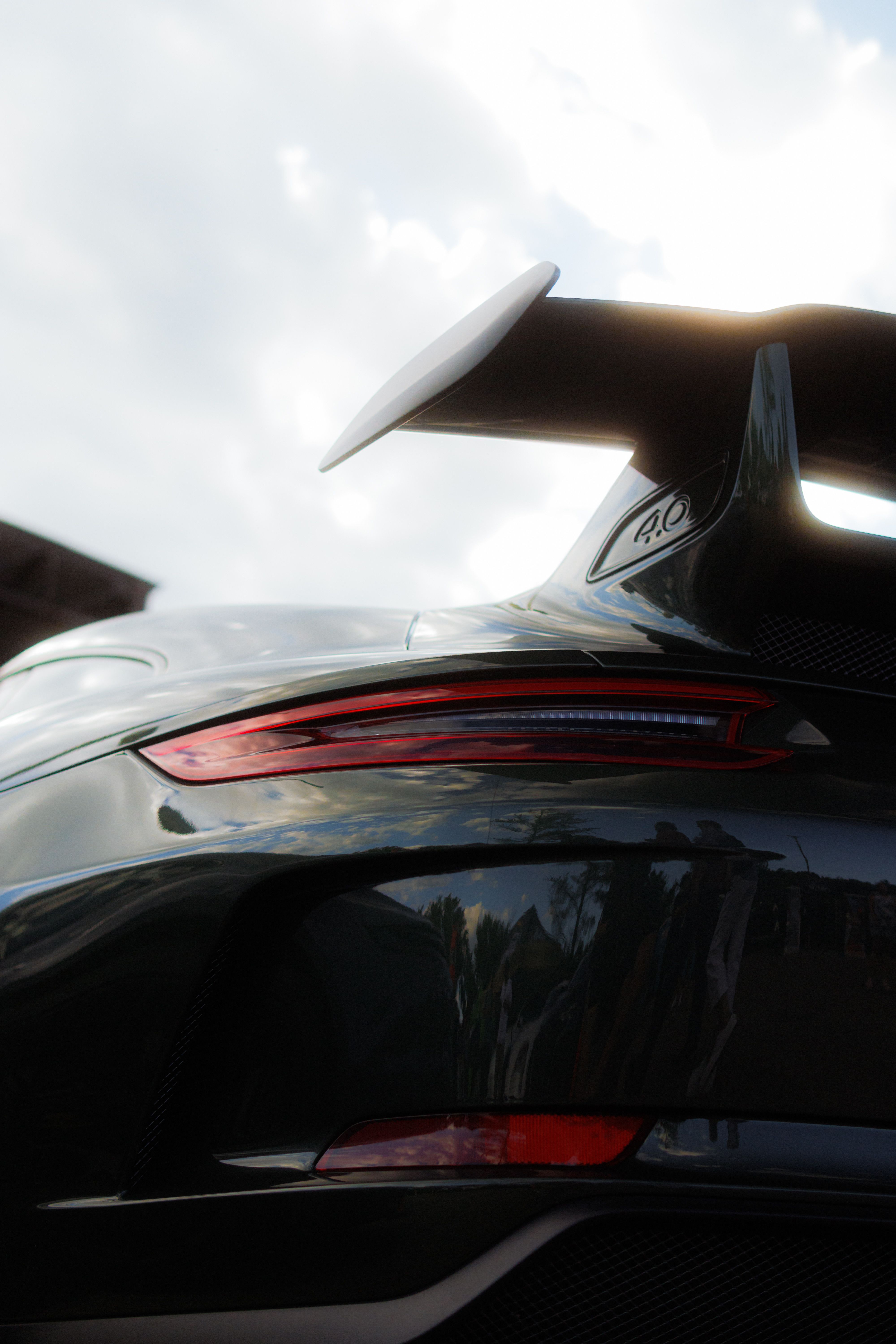 Close-up view of a sports car's rear spoiler and taillights at sunset.