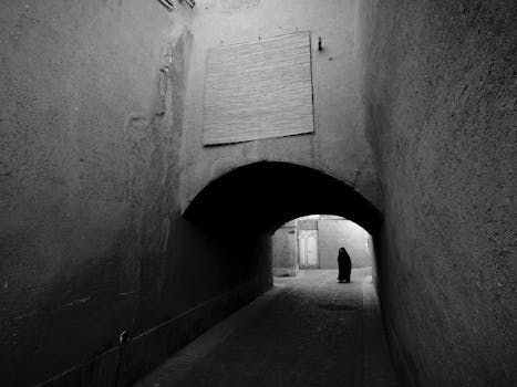 Eerie black and white photograph capturing an alleyway in Yezd with a solitary figure.