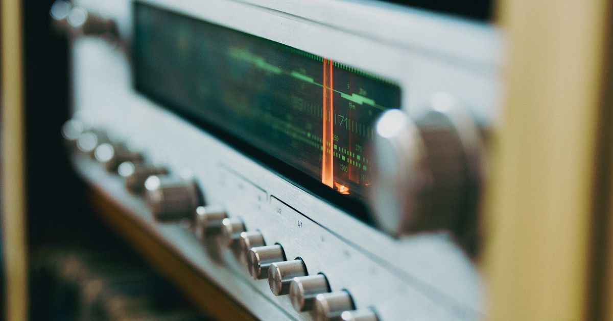 Close do dial de um rádio antigo, com o mostrador analógico iluminado e os botões de sintonia em destaque