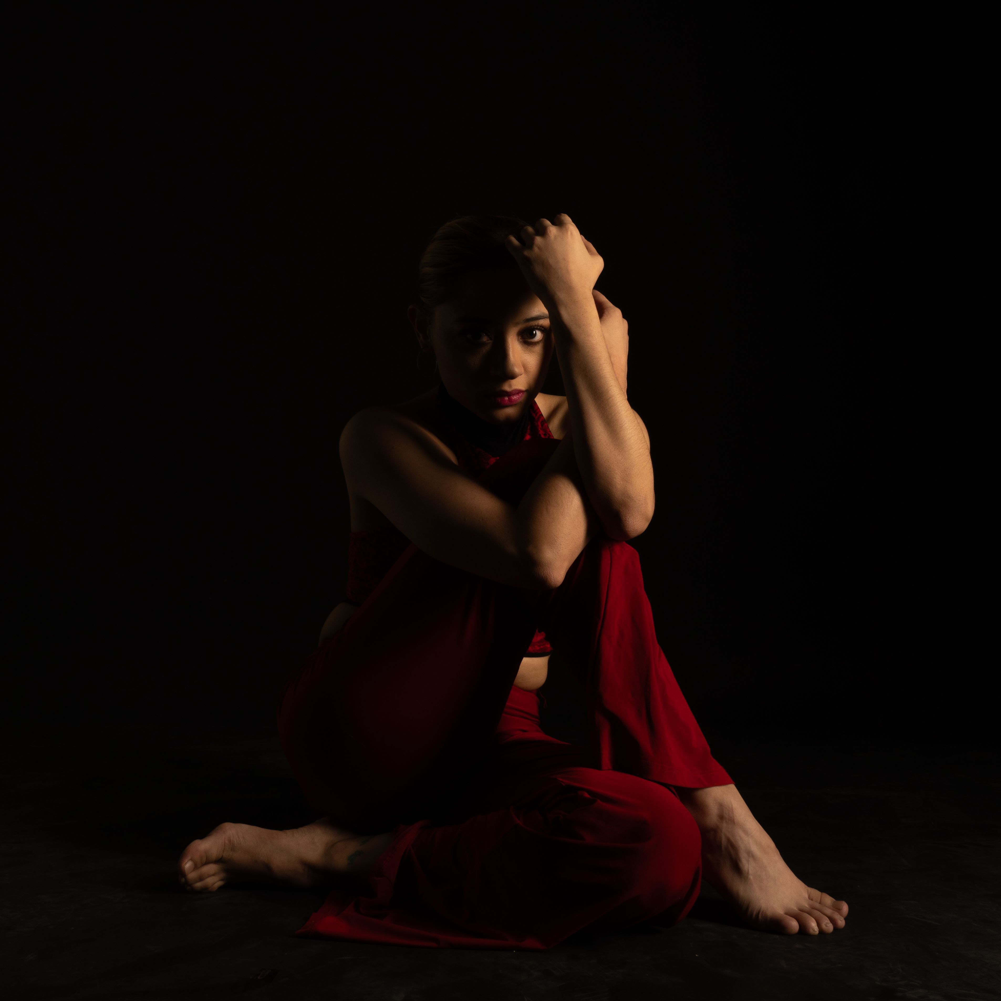 A dramatic portrait of a woman sitting in a dark room, Mexico City.