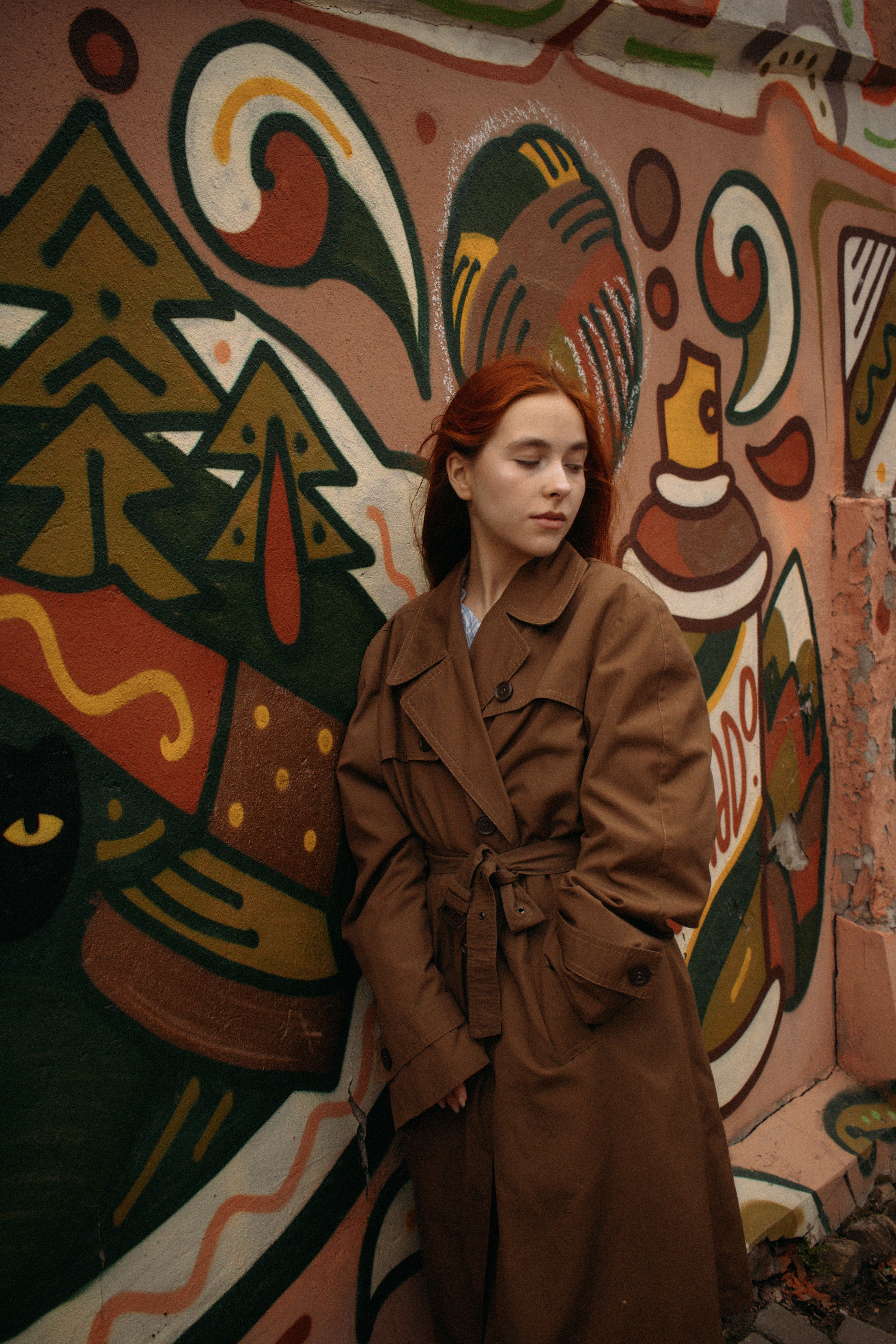 Artistic portrait of a woman standing by a colorful mural in Tomsk, Russia.
