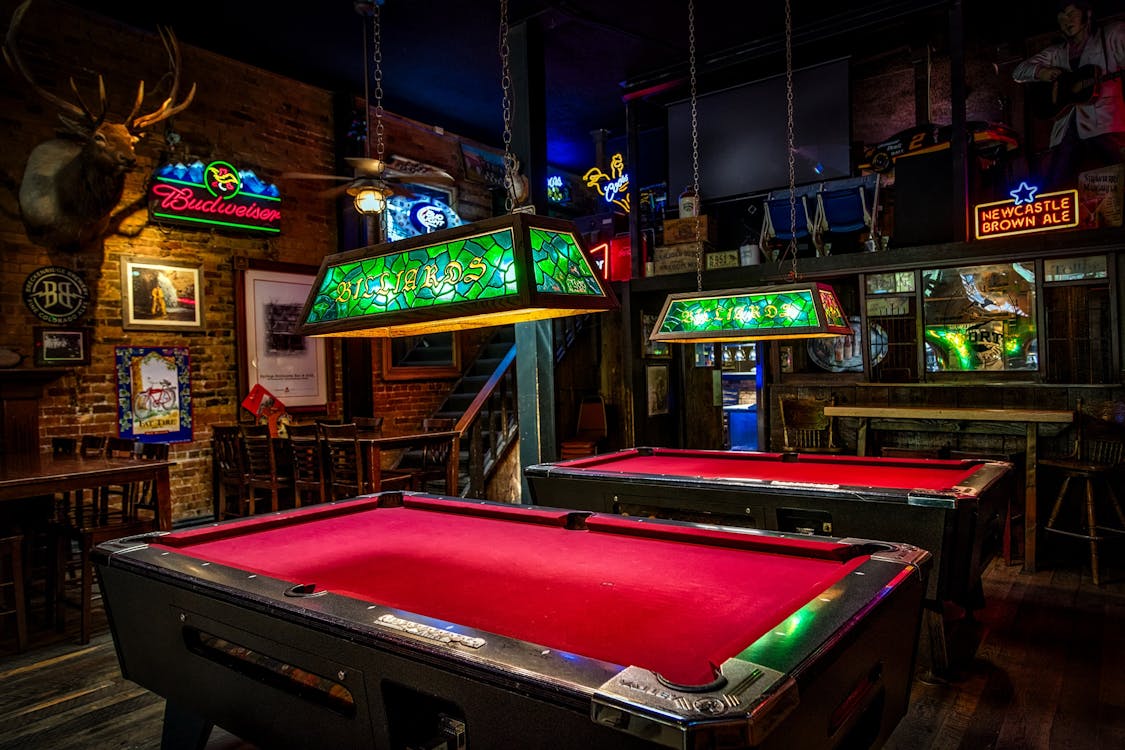 Brown and Red Billiards Tables With Green Lamps