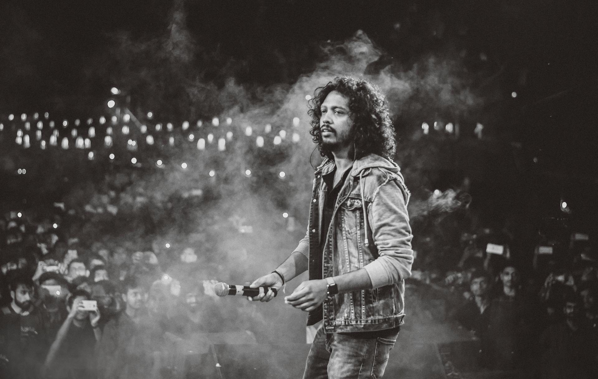 A captivating black and white photo of a performer on stage at a lively concert.