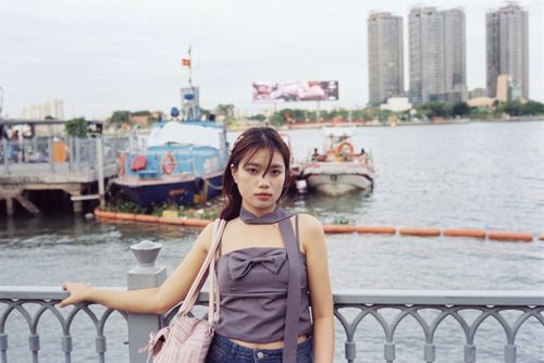 Free Young woman posing by a riverside with skyscrapers and boats in the background. Stock Photo