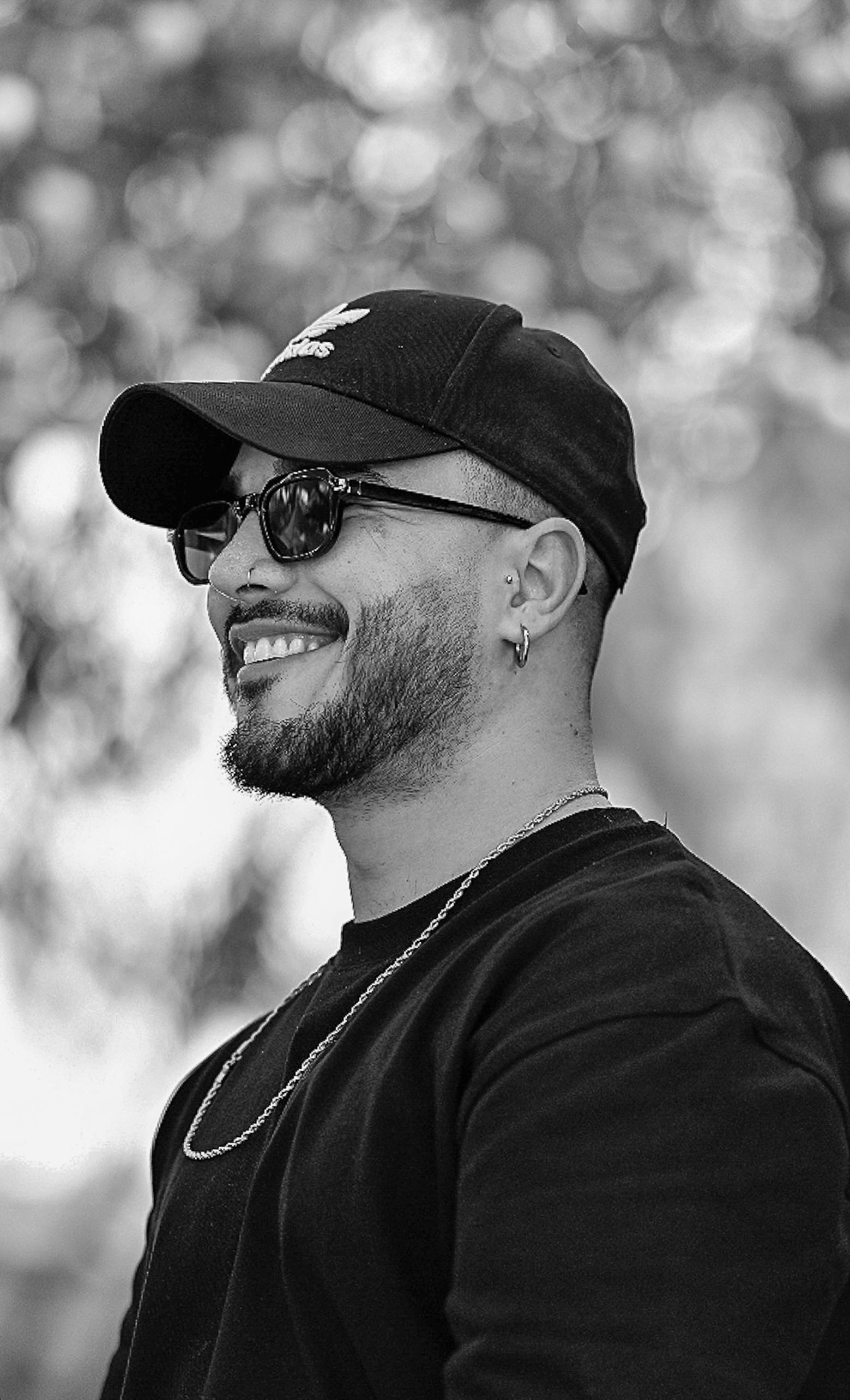 A joyful man wearing sunglasses and a cap, captured in side profile.