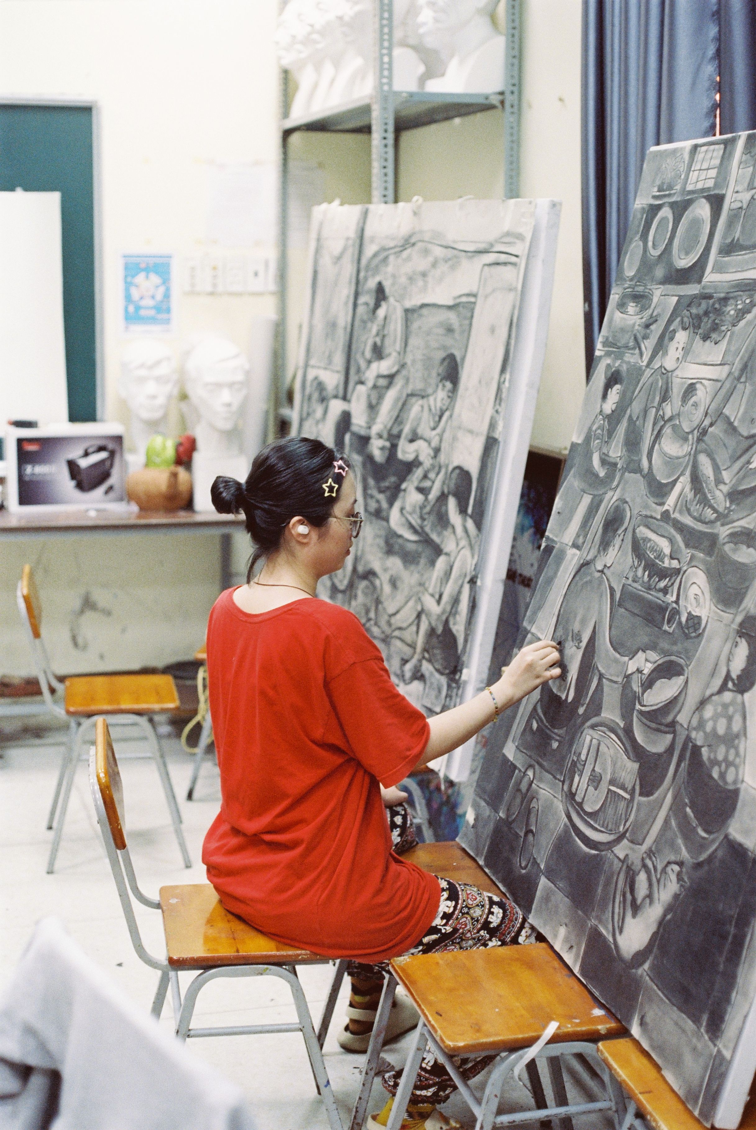 A woman focused on creating a detailed charcoal sketch in an art studio.