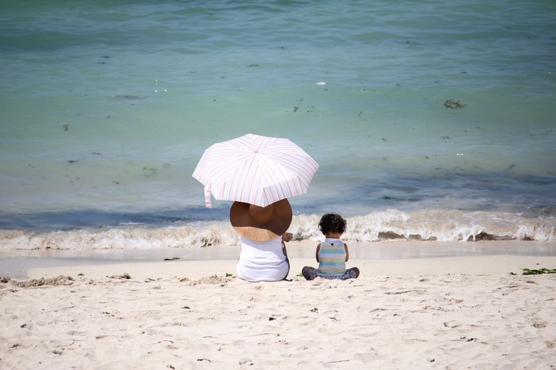 Rodzina odpoczywająca na plaży pod parasolem