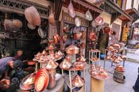 繁华的市场里，充满活力的摊位展示着传统的铜炊具