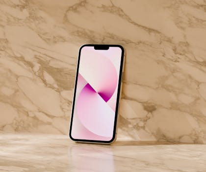 A modern smartphone with a pink abstract wallpaper, resting on a marble surface.