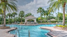 豪华度假村的棕榈树、凉亭和清澈蔚蓝的海水营造出令人放松的热带池畔场景