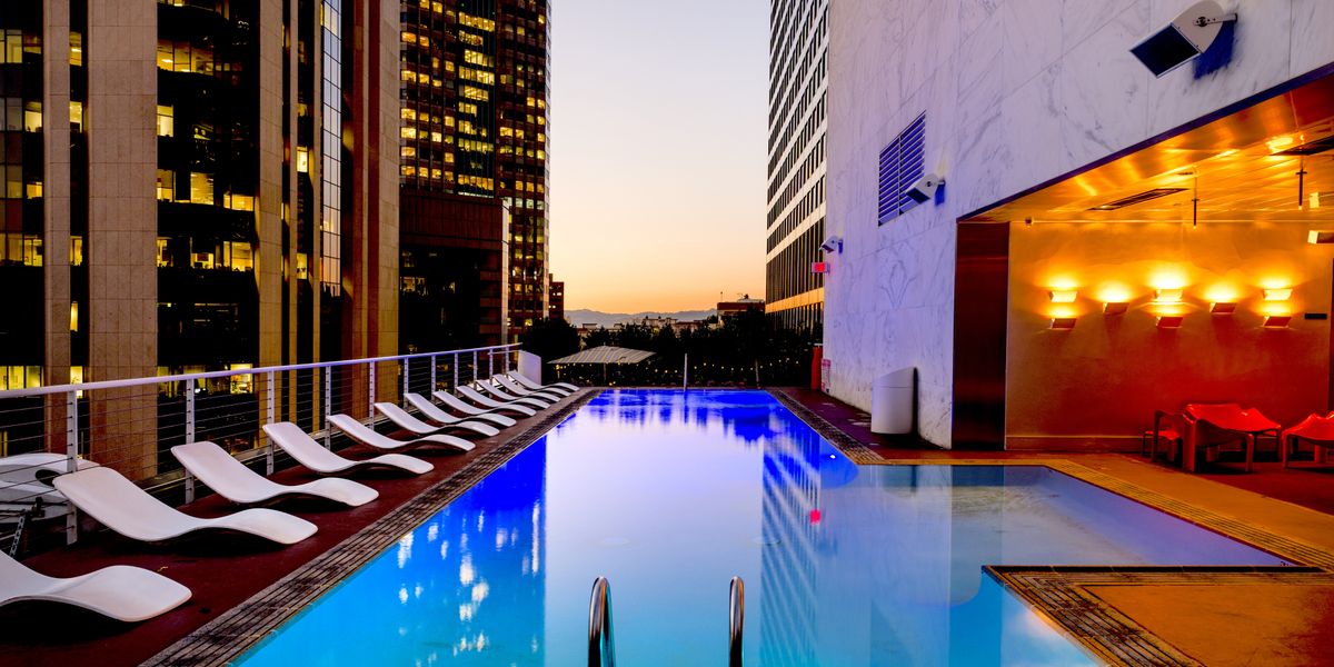 Rooftop hotel pool overlooking a city skyline at sunset