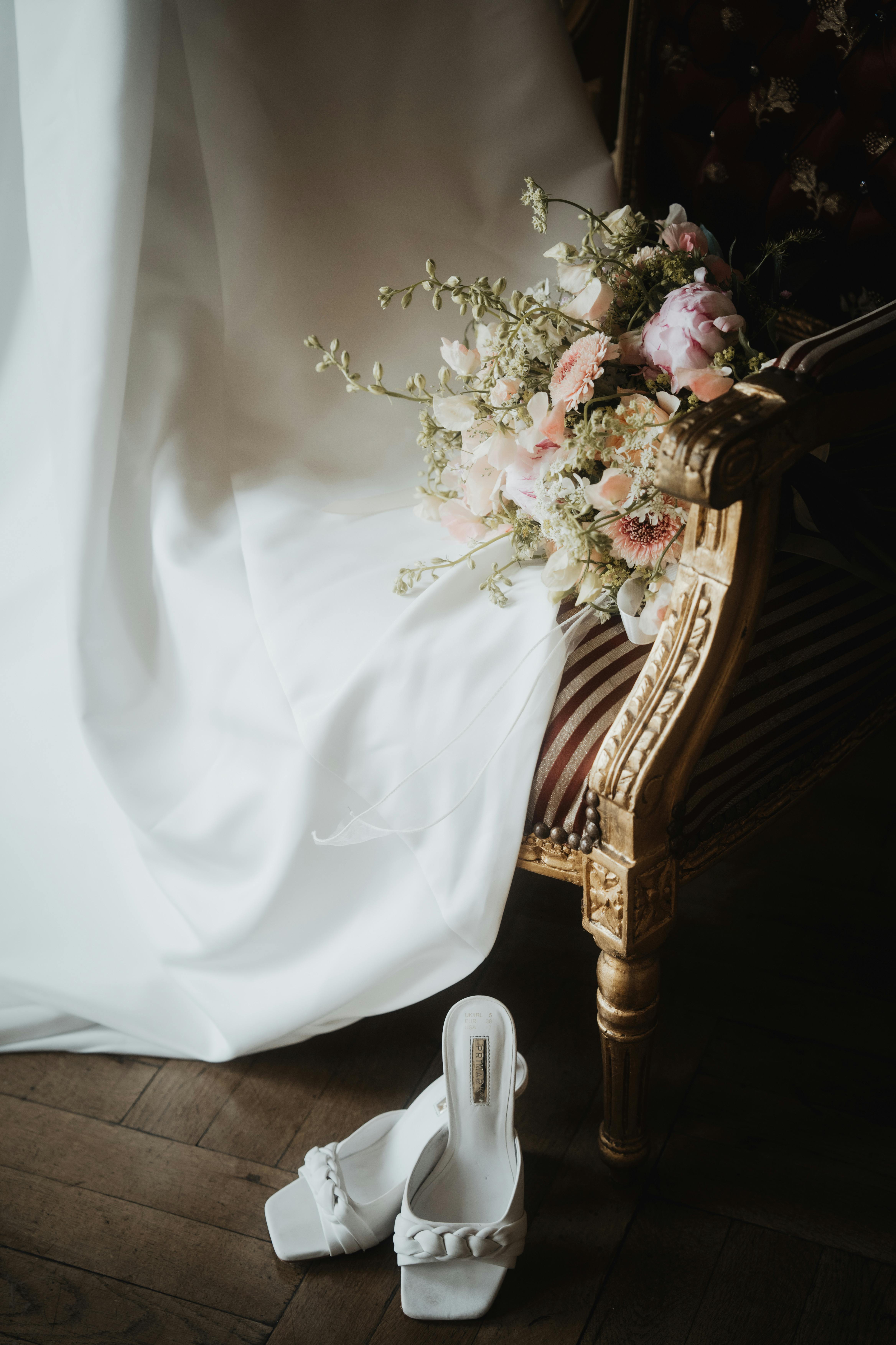 A delicate wedding bouquet and shoes on a vintage chair, epitomizing elegance and style.