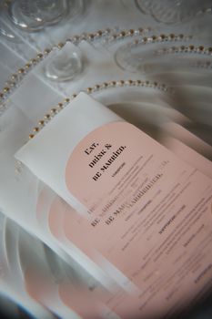 Close-up of elegant pink wedding invitation on a decorative plate setting.