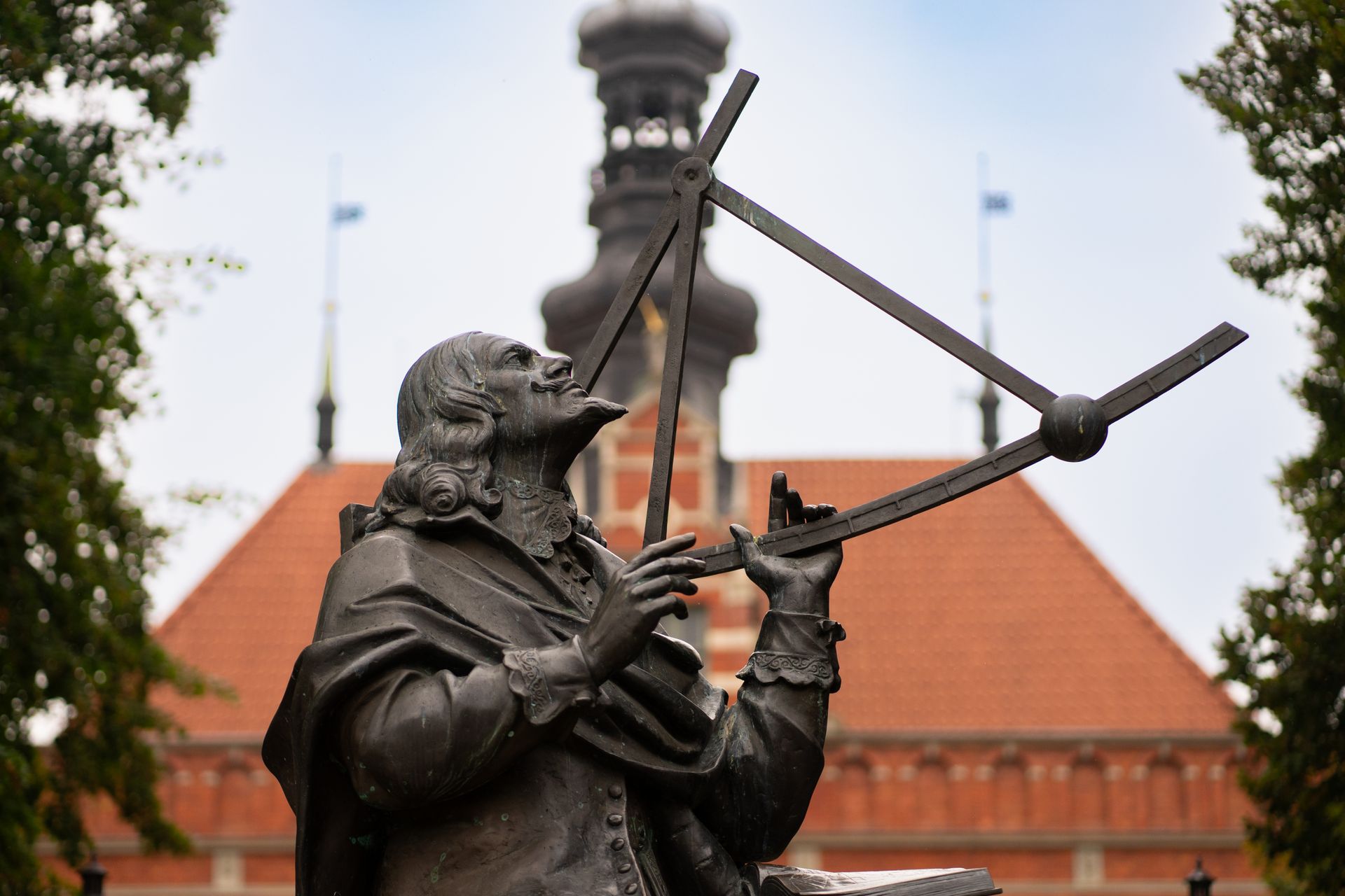 Bronze statue of Johannes Hevelius in front of a historic building in Gdańsk.