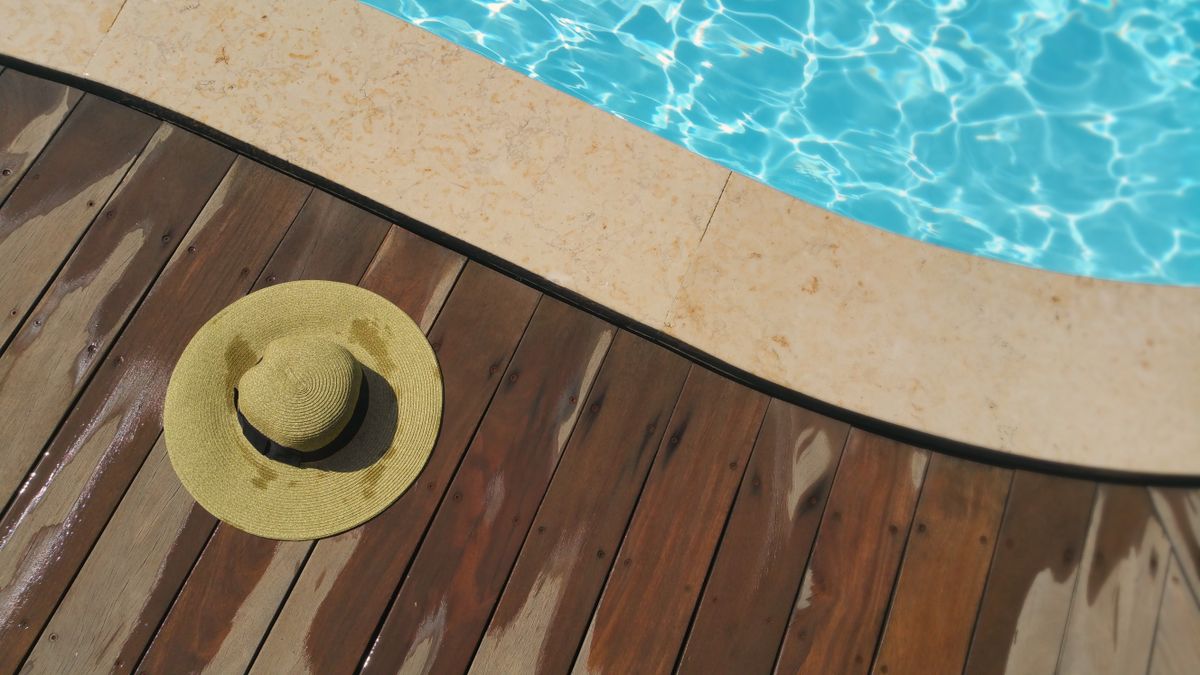 Wooden pool deck beside a clear blue pool