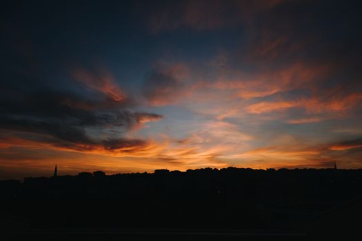 Silhouetted skyline with dramatic clouds during a vibrant sunset.