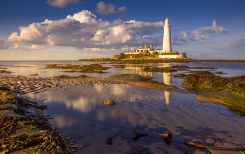 A lighthouse sits on the shore of a body of water