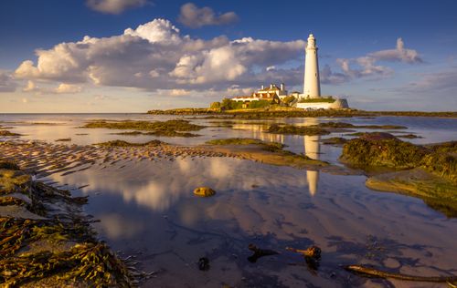 Free Capture of St Mary Lighthouse with dynamic clouds reflecting in the tide pool. Stock Photo