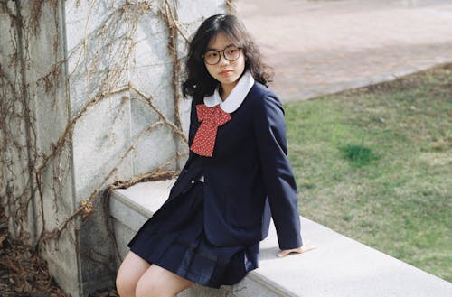 A girl in a school uniform sitting on a bench