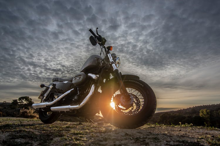 Low Angle Photo Of Black Harley Davidson Forty-Eight 1200 Motorcycle Parked On Dirt Road During Golden Hour