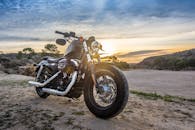 哈雷戴维森摩托车停在户外，在令人惊叹的日落天空映衬下，非常适合用作冒险和旅行的图像