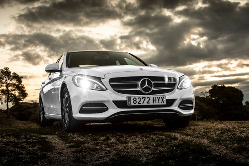 Free White luxury car parked outdoors under a dramatic sunset sky. Stock Photo