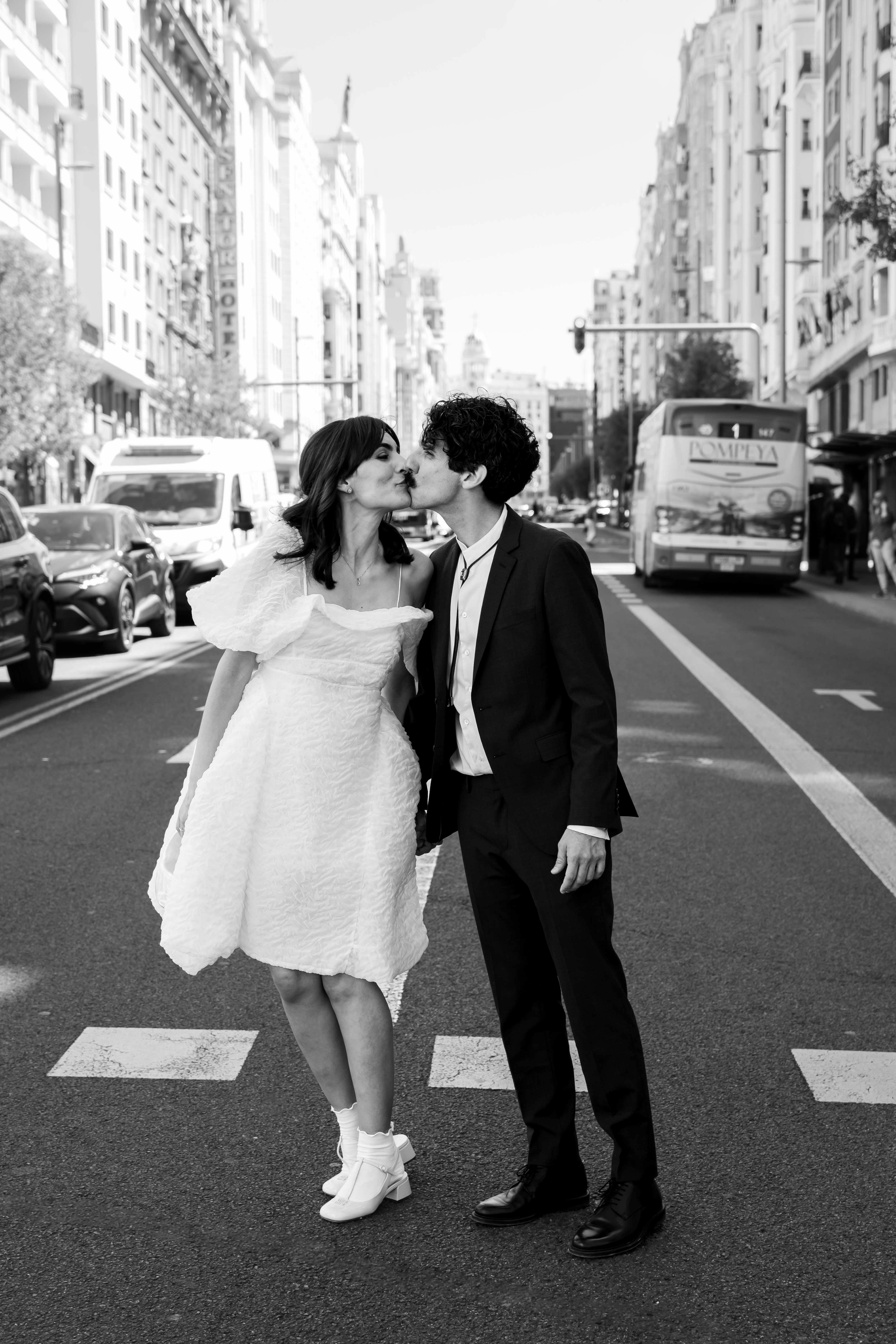 Black and white photo of a couple kissing on a busy street in Madrid, Spain.