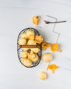 Fresh peeled potatoes and chanterelle mushrooms on a marble surface, perfect for cooking inspiration.
