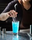 在室内酒吧里，调酒师熟练地搅拌着清爽的蓝色鸡尾酒
