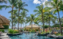 棕榈树、游泳池和清澈的蓝天构成了令人放松的热带度假胜地场景