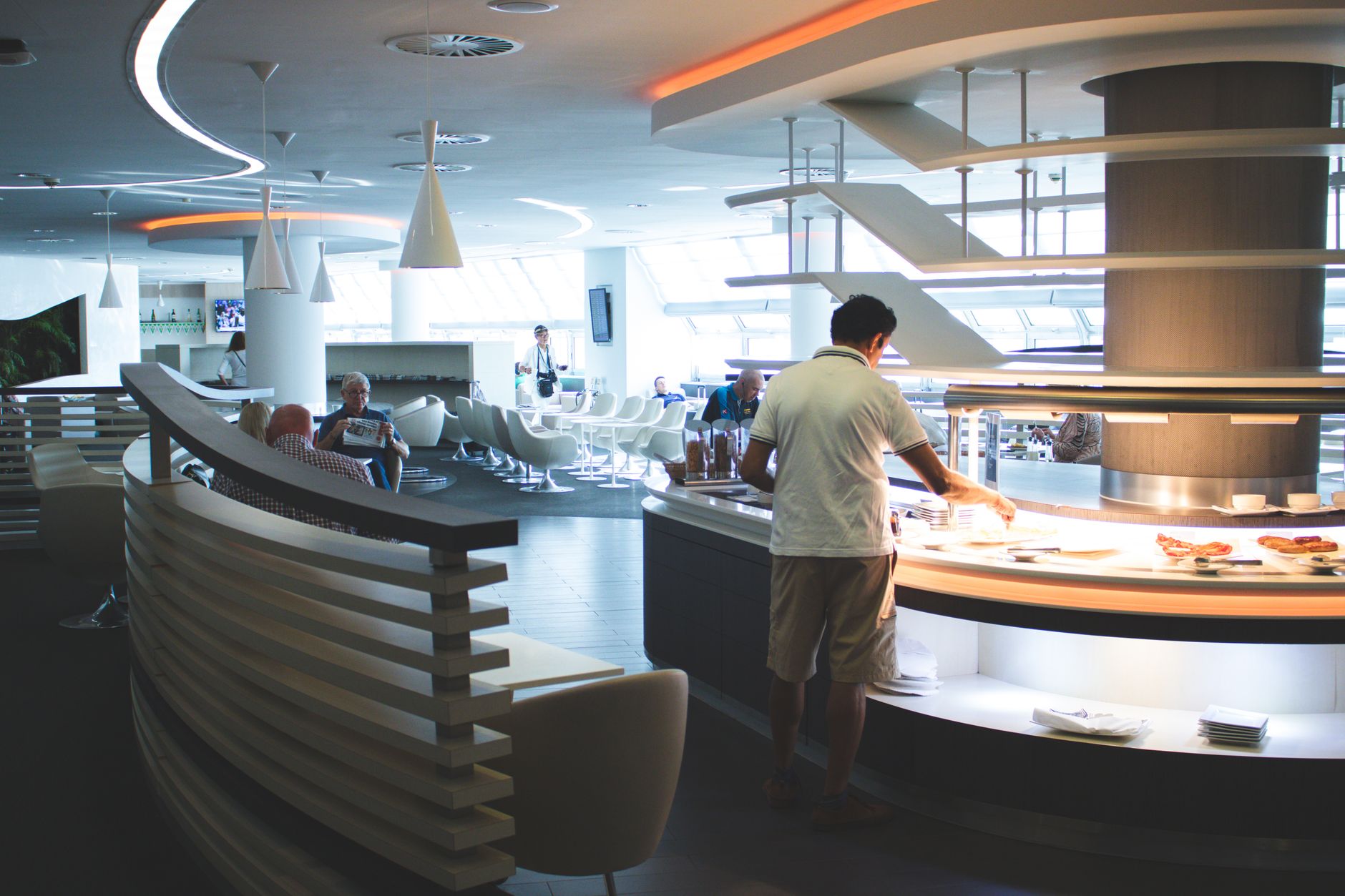 Stylish airport lounge with buffet and seating, featuring sleek interior design and contemporary furniture.