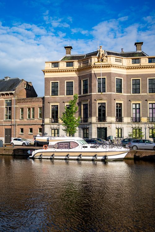 Free Charming Haarlem canal scene with historic buildings and a moored boat on a sunny day. Stock Photo