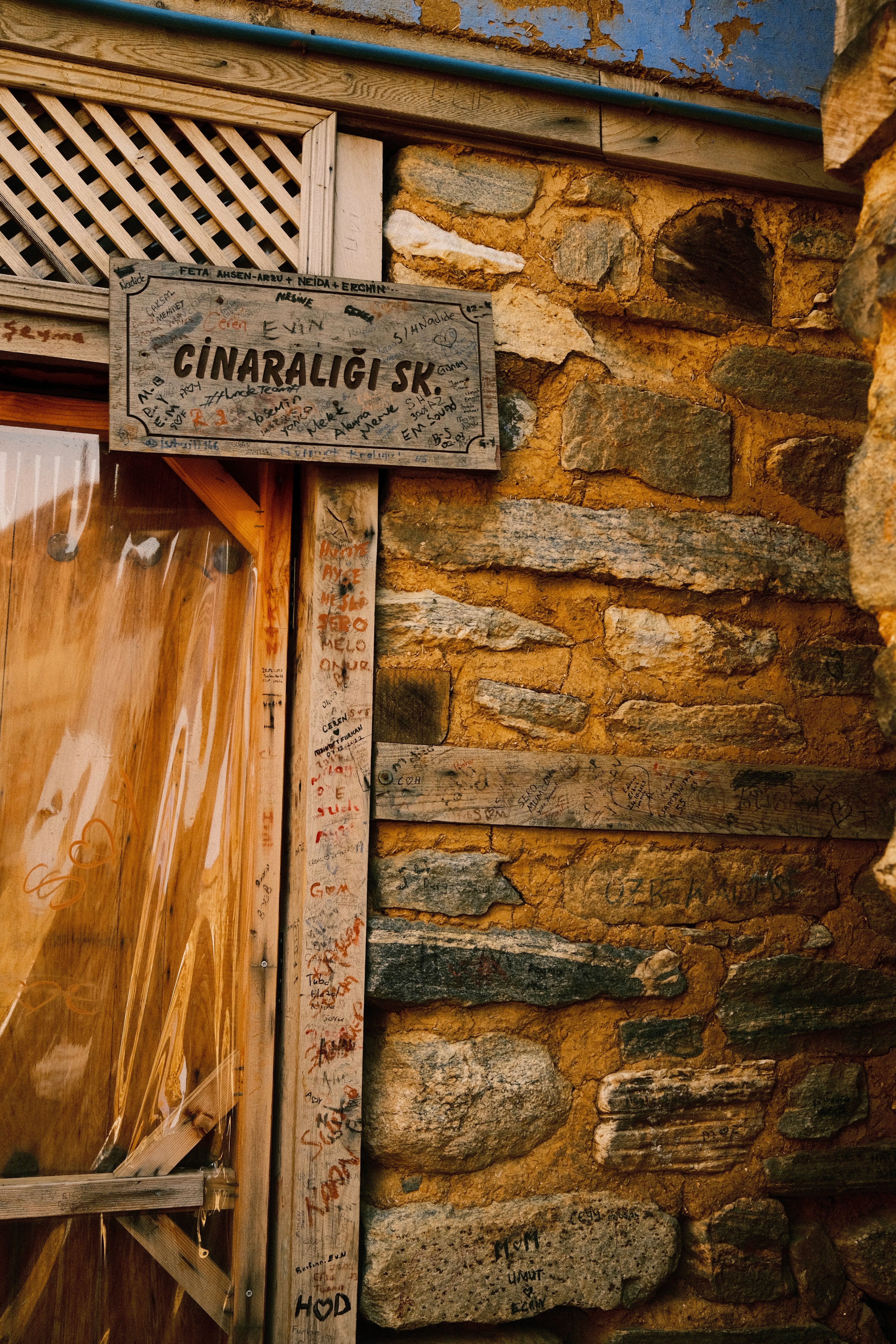 Vintage wooden sign on a stone wall in Çınarlıgi Street, Bursa, Türkiye.