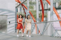 两个微笑的女人手牵着手，走在一座充满活力的现代桥上