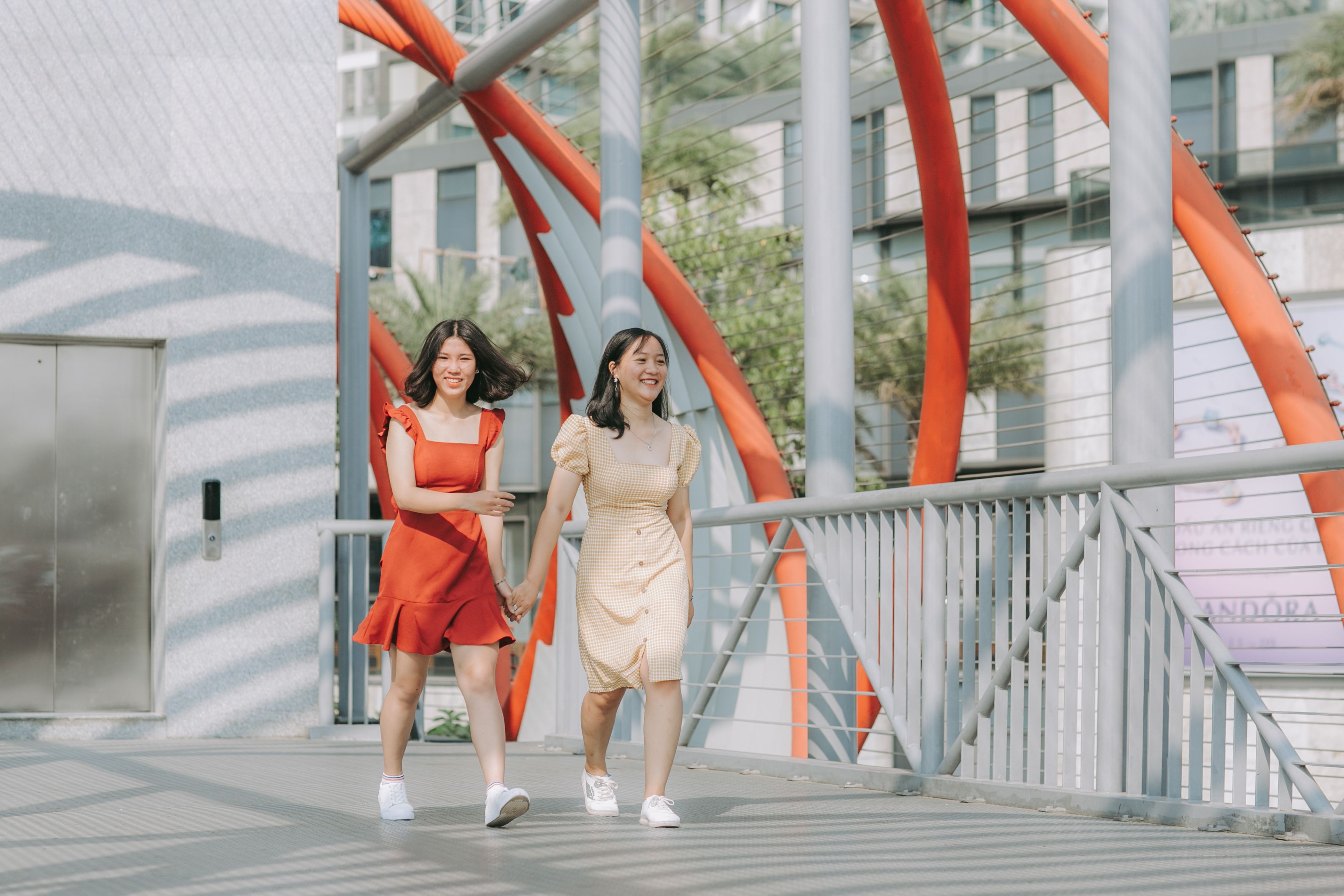 Photo of Two Smiling Women Walking While Holding Hands