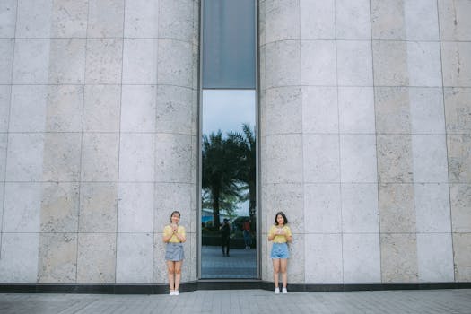 两名妇女站在一座现代建筑旁，建筑有反光玻璃和混凝土墙