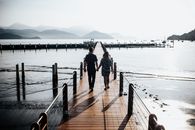 一对夫妇手牵着手，沿着码头漫步，俯瞰着宁静的湖泊