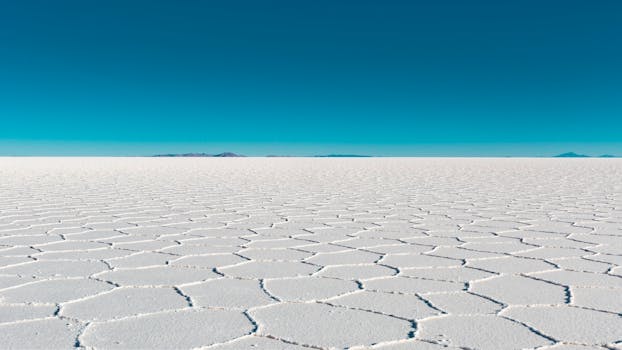 Vast salar with geometric patterns under a clear blue sky in Bolivia's Uyuni.