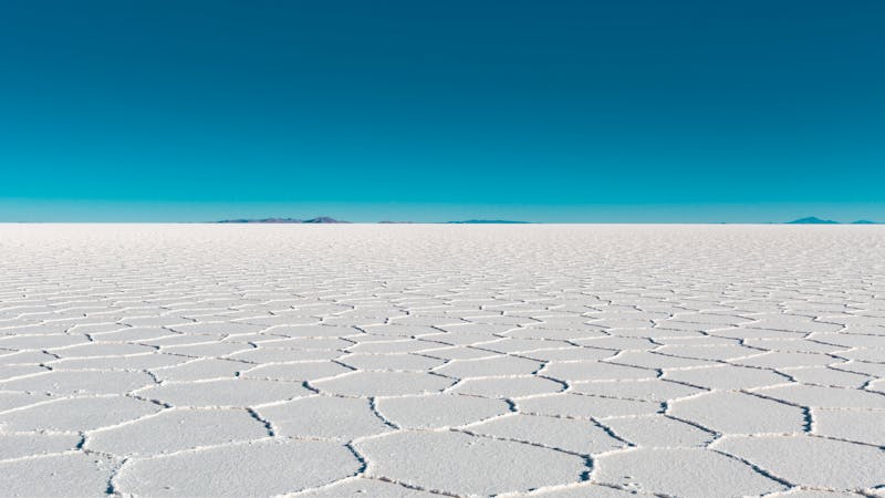 Vaste salin avec des motifs géométriques sous un ciel bleu à Uyuni, Bolivie
