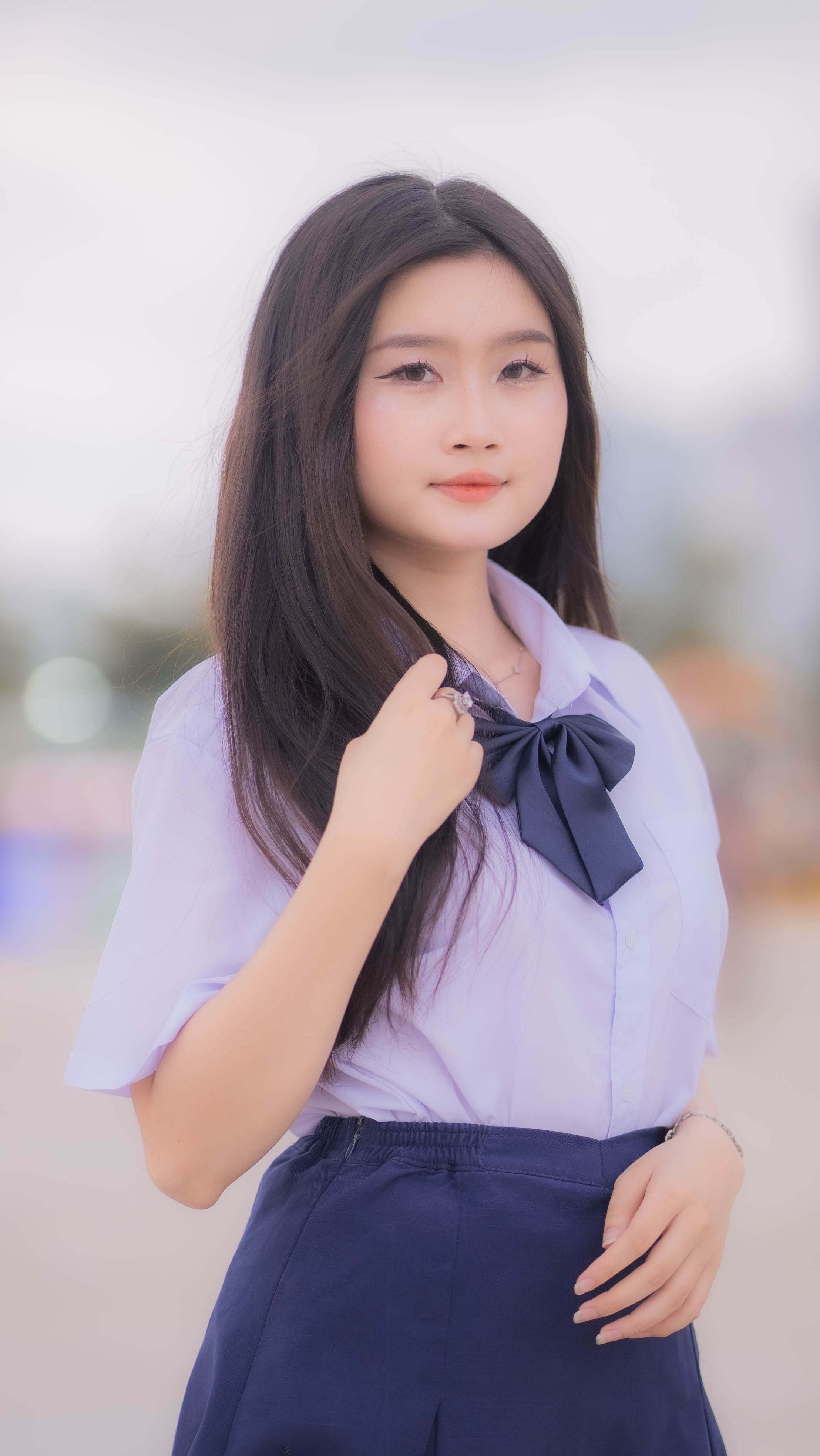 Portrait of a young woman with long black hair in a stylish purple outfit, standing confidently outdoors.