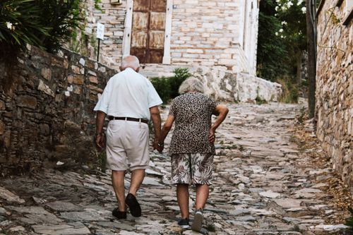 Free An elderly couple holding hands, walking up a cobblestone street in Türkiye. Stock Photo