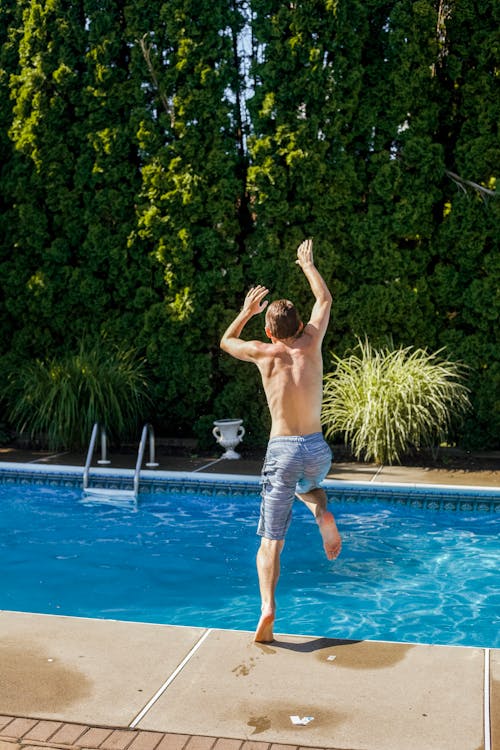 男子跳進游泳池的照片