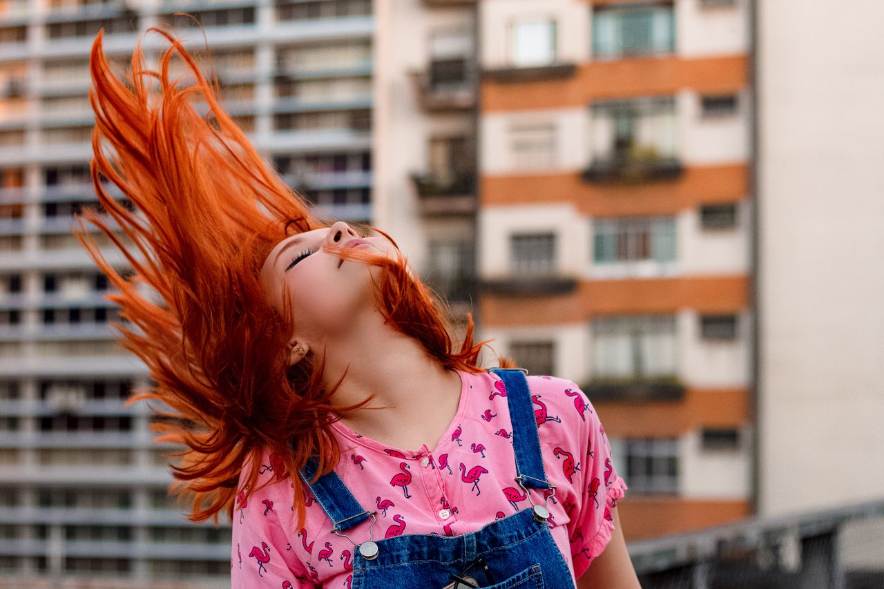 vibrant portrait of a woman flipping her red hair outdoors captivating