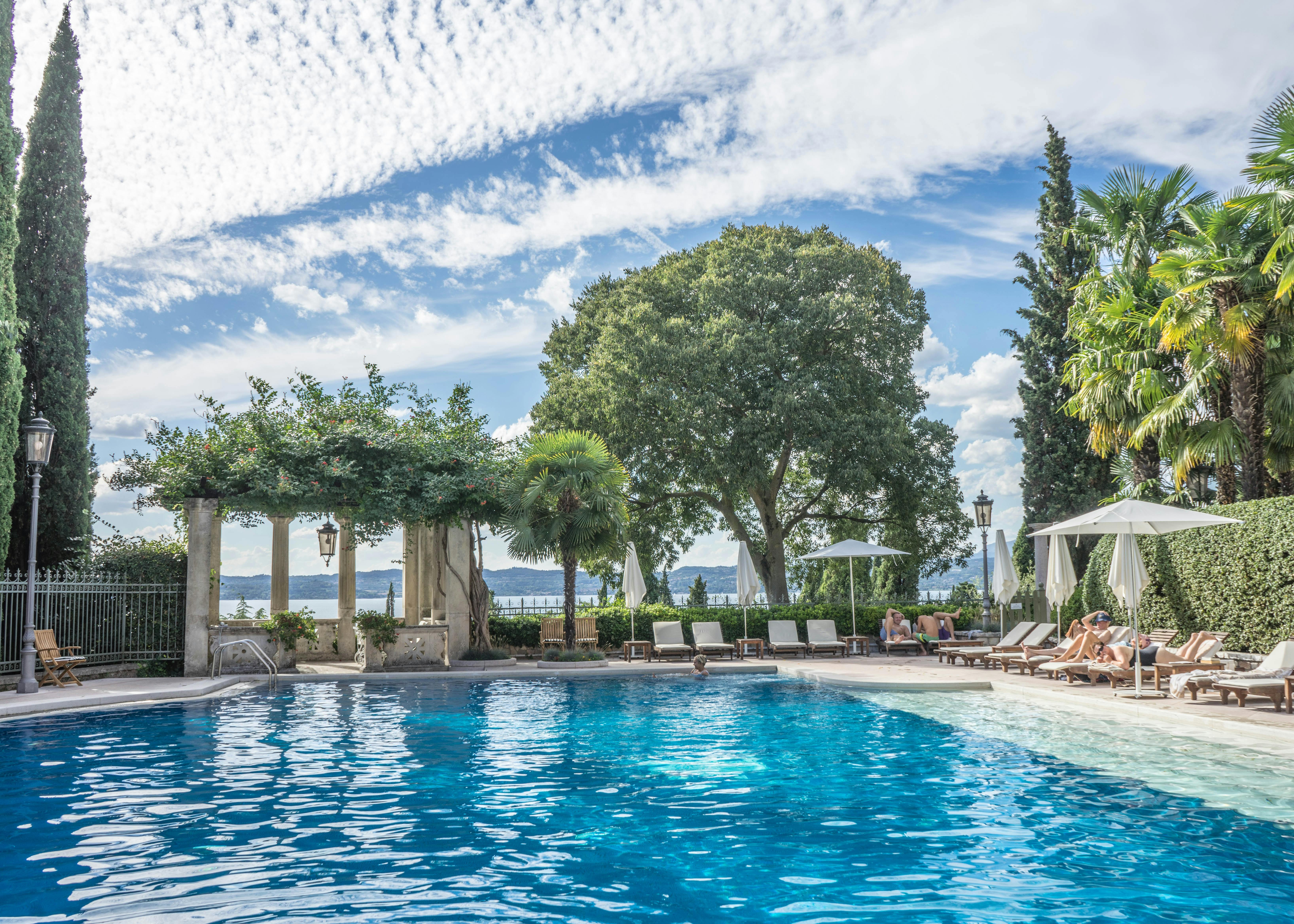 pool near trees and loungers under cloudy sky