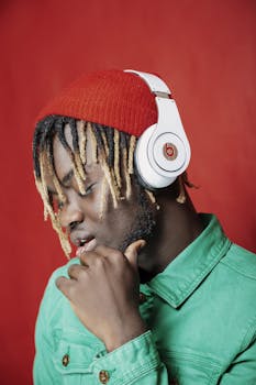 红色背景下，一位穿着绿色夹克、戴着耳机的时尚男子