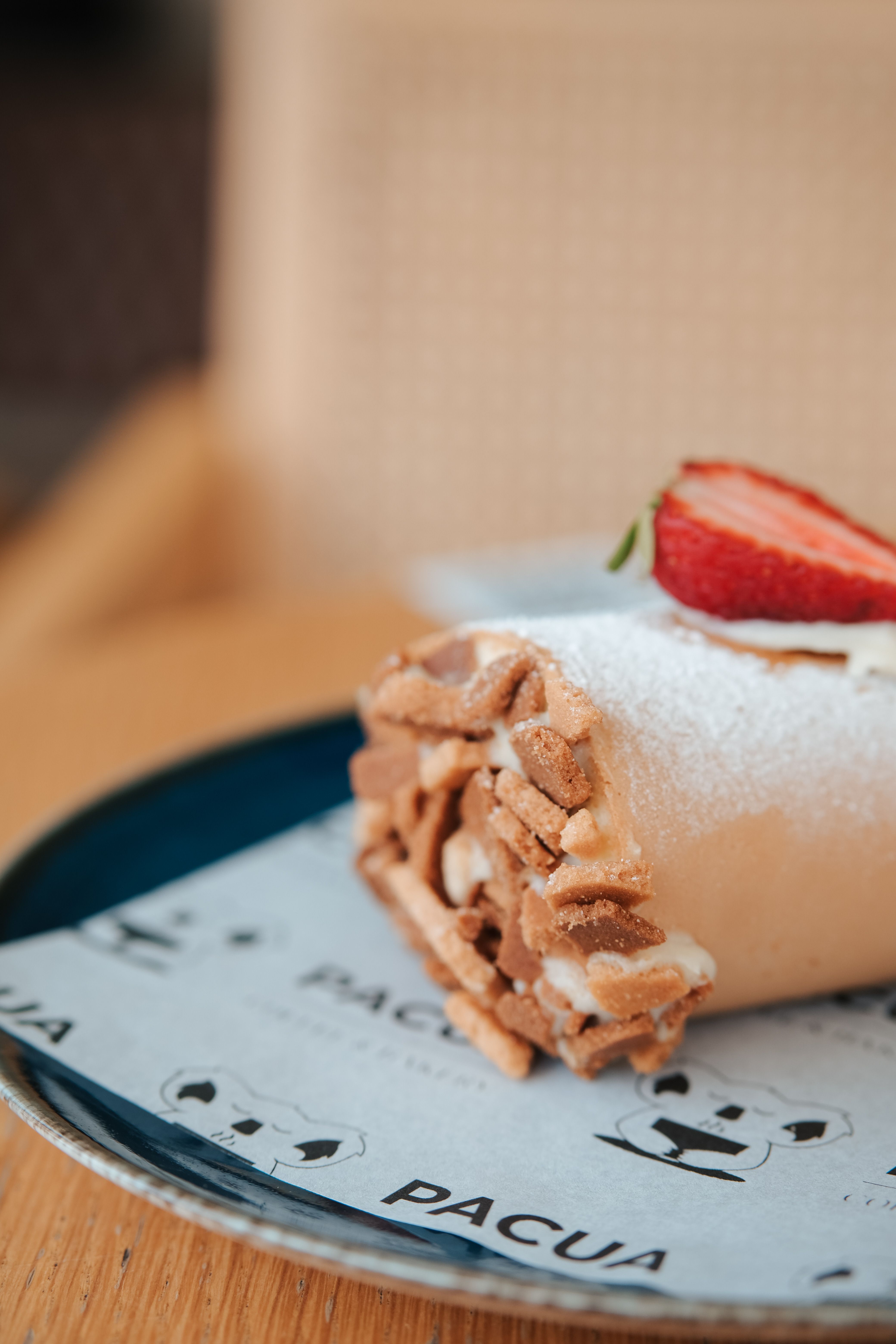 Tasty rolled dessert with strawberry slice on a plate, perfect for food photography.